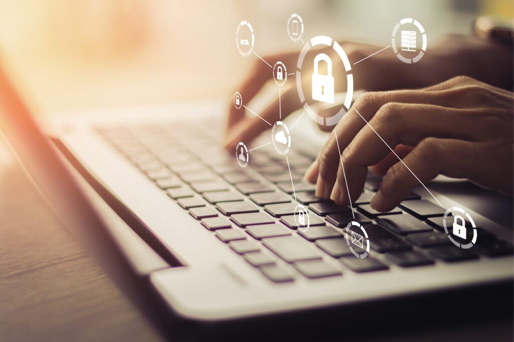 A landscape image of hands on a keyboard. Icons showing locks hover above the hands. Locks show the security of the laptop being used and what is being protected.