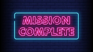 Landscape image of the words 'mission complete'. Both words are in neon pink with a neon blue border around the words.