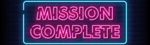 Landscape image of the words 'mission complete'. Both words are in neon pink with a neon blue border around the words.