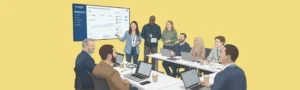 Group of people working around a table looking a large screen dashboard